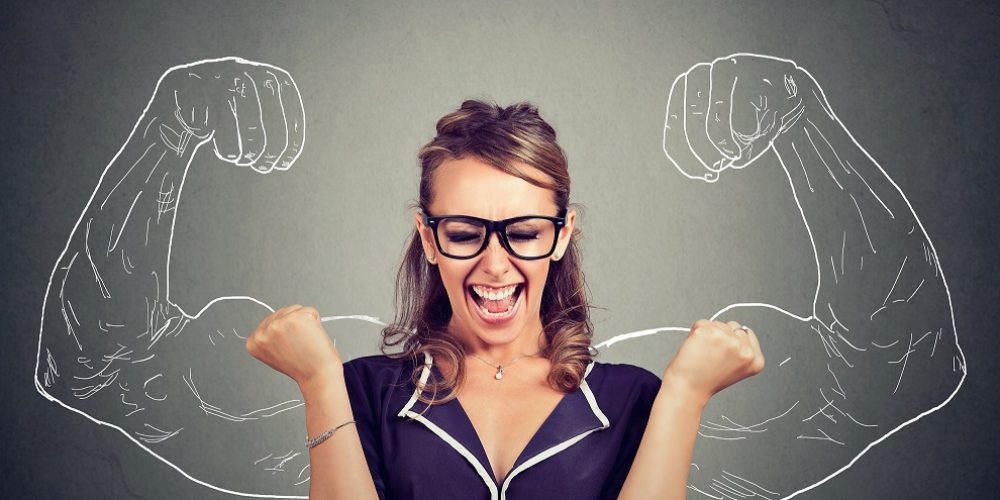 Resilienz happy woman exults pumping fists celebrates success on gray wall background